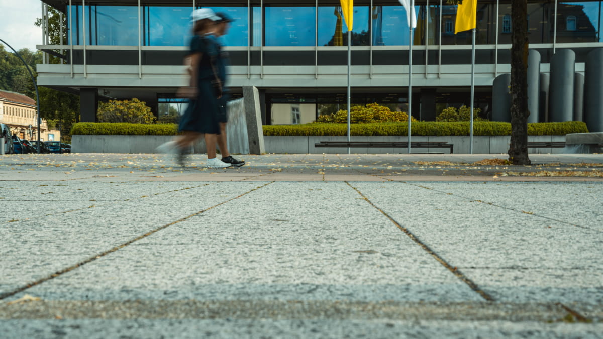Bodentiefe Aufnahme der großformatigen Granitplatten am Coburger Bahnhofsplatz mit vorbeigehenden Passanten – Referenzprojekt von Christian Knoch Tiefbau.