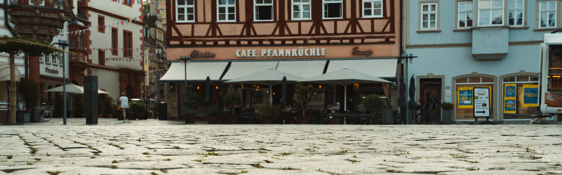 Panoramaaufnahme des gepflasterten Coburger Marktplatzes mit historischen Fachwerkhäusern und Gastronomie